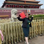 Гостья тура СПР у входа в Запретный город в Пекине с китайским флагом